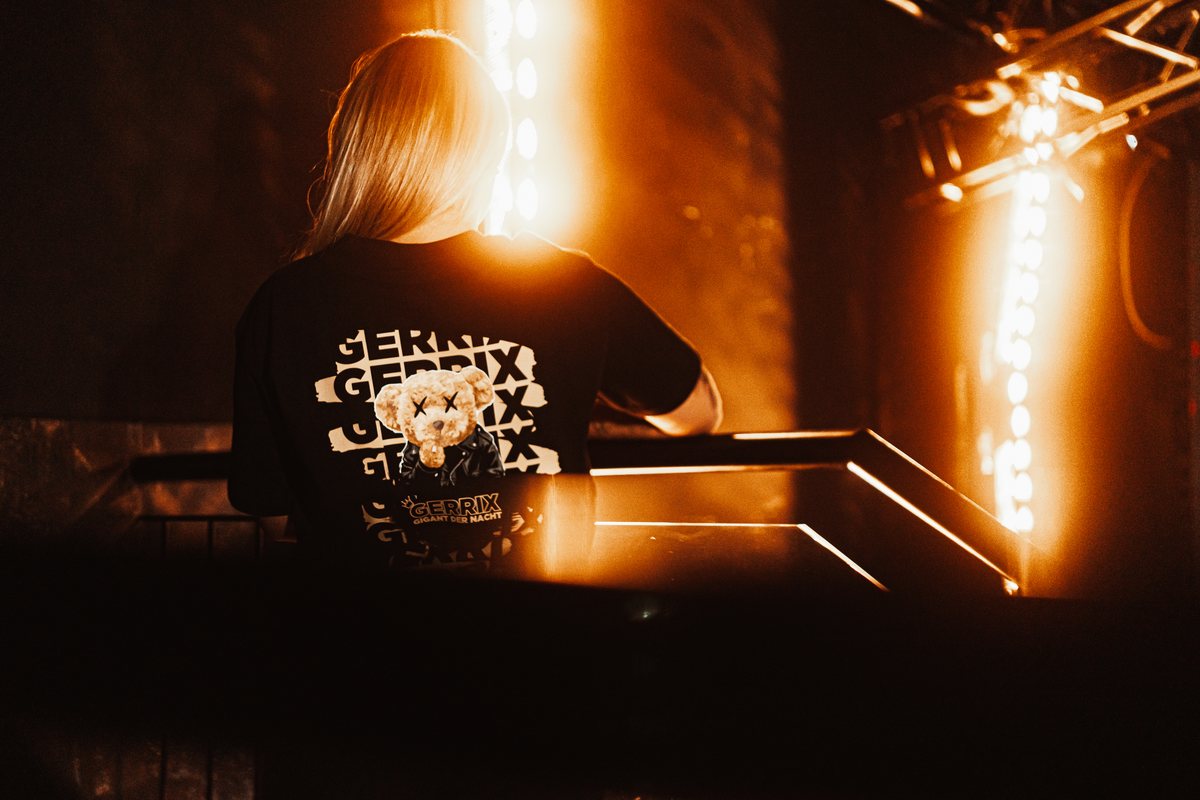 Schwarzes individuell bedrucktes Shirt in einer stimmungsvoll beleuchteten Veranstaltungsszene, von hinten fotografiert