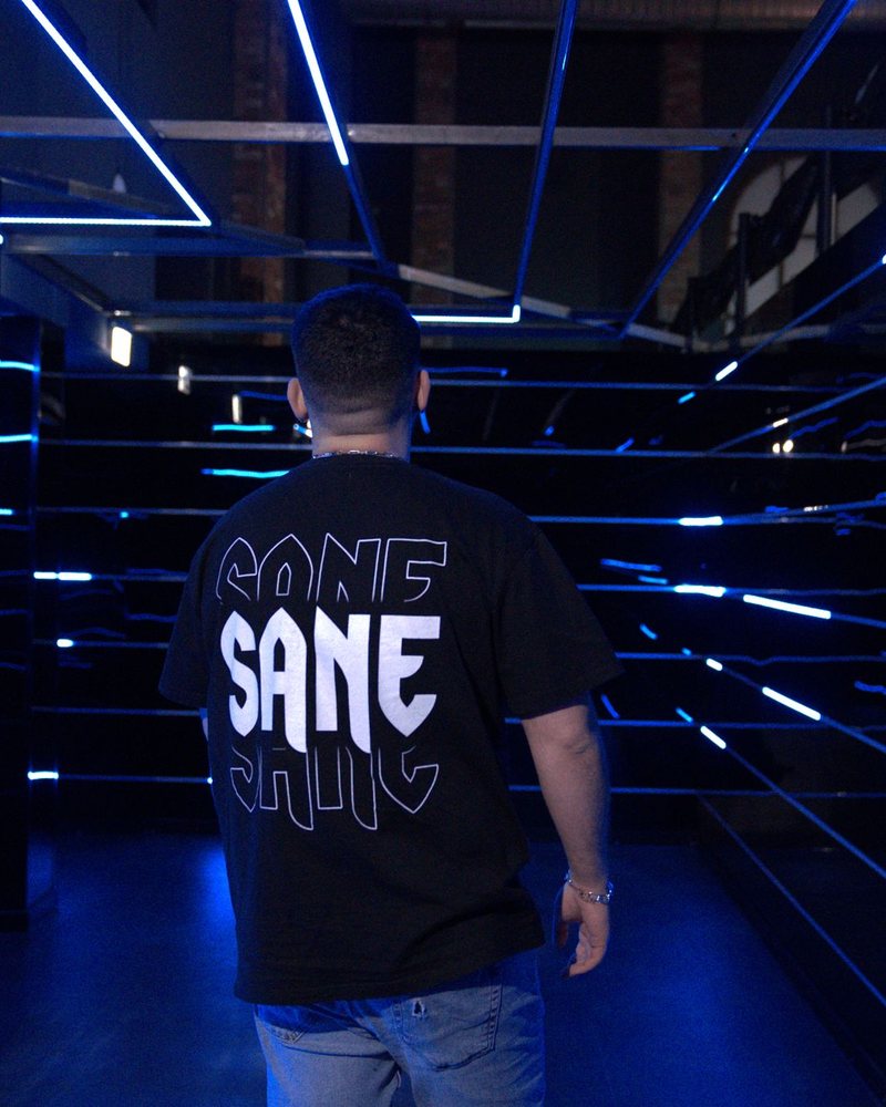Schwarzes Statement-Shirt in einer blau beleuchteten Umgebung, von hinten fotografiert